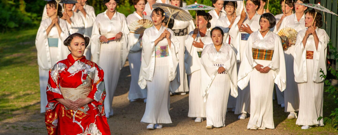 Yitian Luan (Foto) und Tetiana Miyus wechseln sich in der Rolle von Cio-Cio-San ab, hier mit dem Chor der Eutiner Festspiele. Foto: EFS Yitian Luan (Foto) und Tetiana Miyus wechseln sich in der Rolle von Cio-Cio-San ab. Zudem zu sehen: Der Chor der Eutiner Festspiele. Foto: EFS